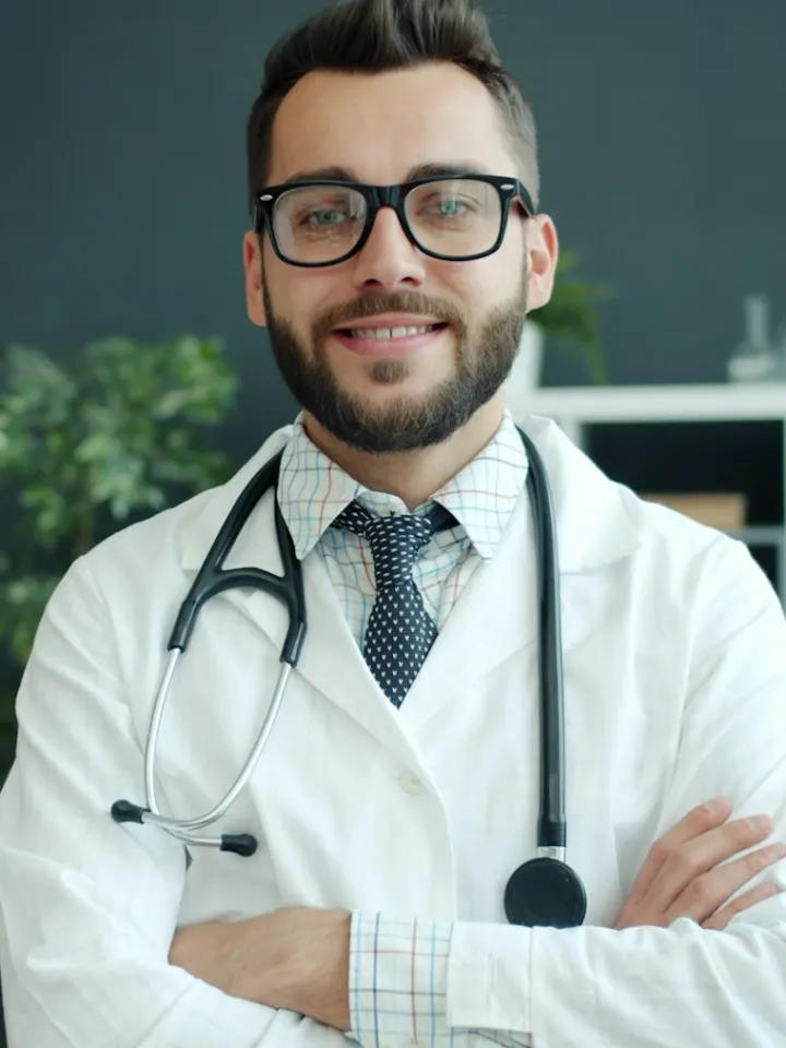 A smiling doctor in a white coat with a stethoscope, arms crossed