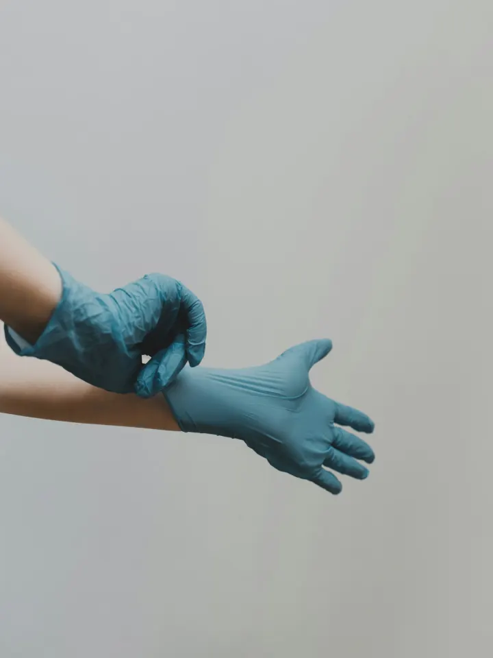 Hands pulling on blue medical gloves